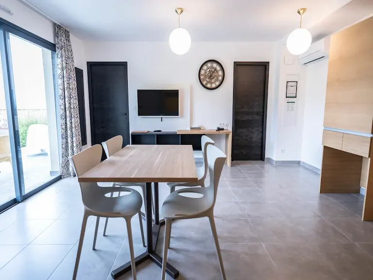Soggiorno con tavolo, televisione e accesso alla terrazza del bilocale Superior